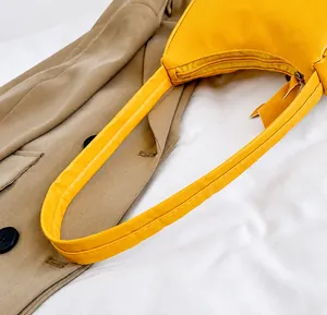 Detailaufnahme des glatten Griffs und Reißverschlusses der gelben Halbmond-Tasche