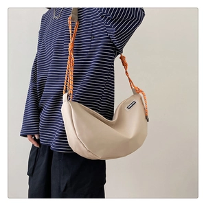 Detail of hobo bag featuring woven rope strap and minimalist brand patch on cream leather