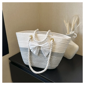 Woven straw tote bag in white and grey gradient with a decorative mesh bow and rope handles