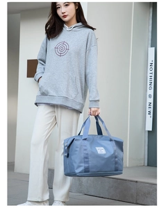 Detalle de la bolsa de viaje de nailon azul con asas y logotipo minimalista