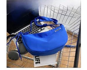 Detail of blue nylon crescent crossbody bag with laptop and lifestyle items