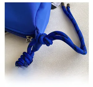 Detailed close-up of the blue nylon bag showing a woven drawstring and metal zipper