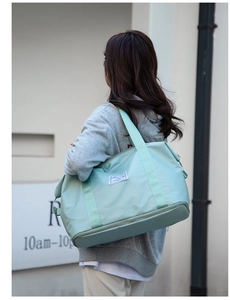 Detalle de bolsa de viaje de nailon verde claro con compartimento inferior para zapatos y logo