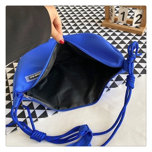 Detail of royal blue nylon crossbody bag featuring knotted strap and interior brand label