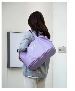 Vista trasera de modelo llevando un bolso de viaje violeta de nailon con correas anchas