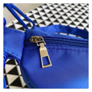 Macro detail of high-density nylon fabric and smooth gold metal zipper on a blue bag