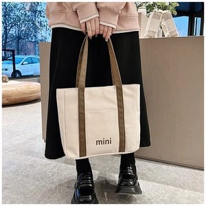 Detalle del mini bolso de lona con asas marrones y tela crema de estilo minimalista coreano