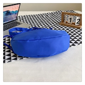 Detail view of the wide round base and drawstring of a large Klein blue nylon shoulder bag