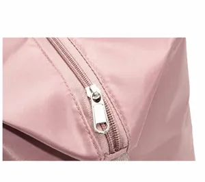 Close-up of silver metal zipper and durable pink nylon fabric on a travel tote bag