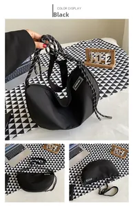 Detail of black nylon crescent bag with thick rope strap and logo label on patterned background