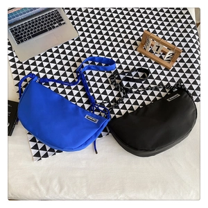 Detail of blue and black nylon crescent crossbody bags with adjustable knotted straps