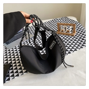 Detail of black crescent crossbody bag with thick black and white woven rope strap