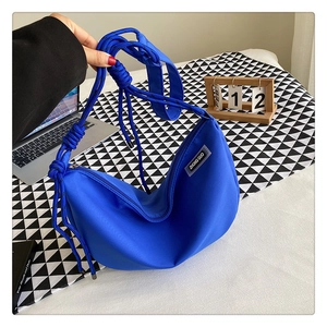 Detail of blue nylon crescent bag featuring a thick braided rope strap and woven label