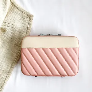 Detail view of pink and beige quilted leather handbag with elegant metal clasp