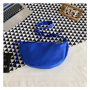 Close-up of royal blue nylon dumpling bag with adjustable drawstring strap on a desk
