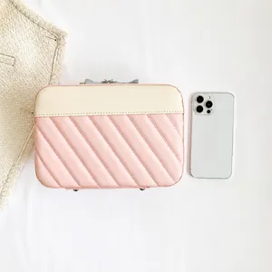 Detailed view of pink and beige quilted square bag shown with smartphone for size reference
