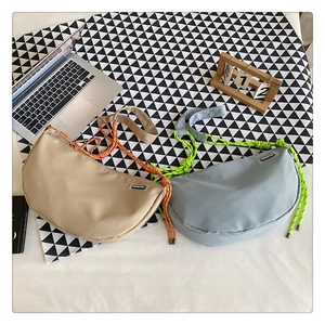 Detail of nylon crescent bags in beige and blue with colorful braided shoulder straps