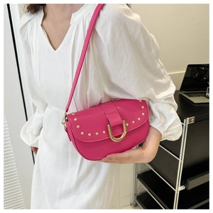 Détail d'un sac bandoulière rose avec boucle mors dorée et finitions à clous dorés