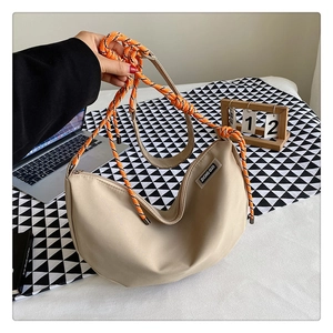 Detail of beige nylon crescent bag with orange woven rope strap and logo patch