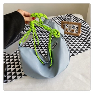 Detail of light blue nylon crescent bag with vibrant neon green cord shoulder strap