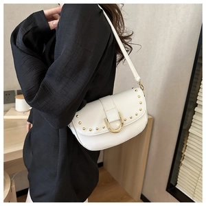 Détail du sac bandoulière blanc avec clous dorés et grande boucle en métal en forme de U
