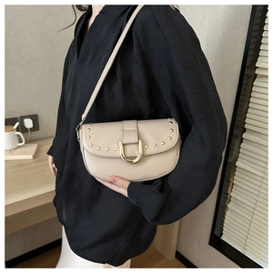 Détail de la sacoche beige avec rivets dorés et boucle en fer à cheval métallique