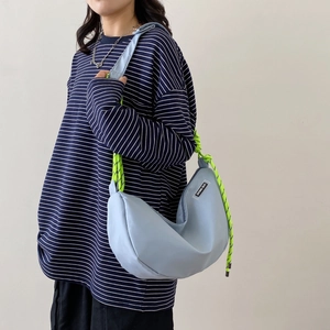 Large blue nylon crescent crossbody bag with vibrant green woven shoulder strap