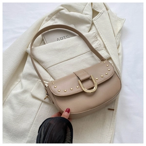 Détail du sac croissant abricot avec rivets dorés et boucle en U sur costume blanc