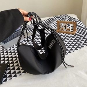 Black nylon crescent crossbody bag with woven rope strap shown in lifestyle setting