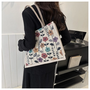Rear view of a large floral jacquard tote bag held by a person in a modern office setting