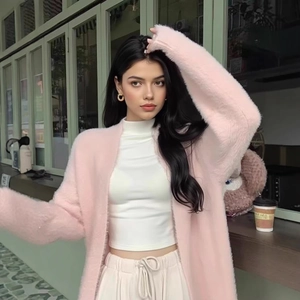 Detailed texture of pink plush knit cardigan with soft mohair feel in cafe setting