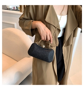 Detailed shot of black glitter evening bag with gold metal handle and chain strap