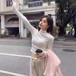 Close-up of white slim-fit mock neck thermal top styled with a pink faux fur jacket