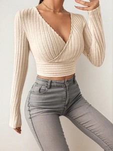 Detail of ribbed beige wrap knit top featuring a deep V-neck and slim fit long sleeves