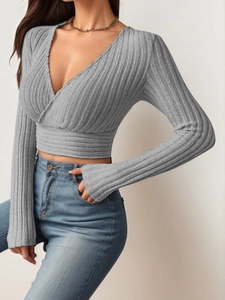 Detail of grey ribbed knit wrap top with deep V-neckline and slim long sleeve design