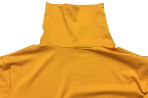 Detailed view of ginger yellow turtleneck collar and smooth knit fabric texture