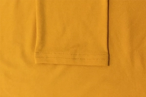 Gros plan sur les finitions à double couture d'une robe longue en maille jaune moutarde