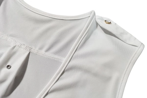 Détail d'une combinaison blanche sans manches avec bouton décoratif chic en strass doré