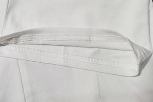 Gros plan sur l'ourlet du combishort blanc montrant la double couture de précision