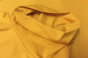 Gros plan du bodysuit jaune gingembre montrant la maille haute densité et le col plissé
