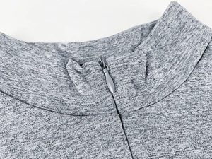 Detail of grey knitted bodysuit featuring a stand collar and metal drop-shaped zipper