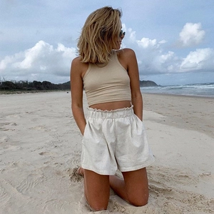 Détail d'un crop top côtelé beige et d'un short blanc à taille haute sur la plage