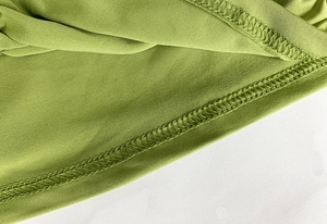 Nahaufnahme von grünem Jersey-Stoff mit hochwertiger Doppelnaht-Overlock-Verarbeitung
