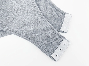 Detail view of the bottom crotch area with three secure white snap buttons on gray bodysuit