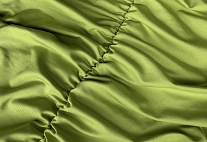 Detaillierte Nahaufnahme von avocado-grünem Strickstoff mit eleganter Raffung und Glanz