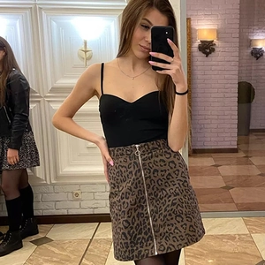 Detail of black slim-fit tank top paired with leopard print mini skirt and ring zipper
