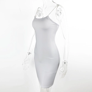 Détail de robe moulante blanche avec fines bretelles en chaîne dorée et décolleté courbé