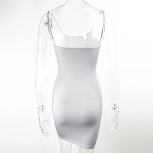 Détail d'une robe moulante blanche avec bretelles chaîne en métal et coupe ajustée
