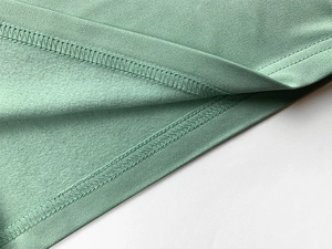 Detailed view of sage green knitted fabric stitching with soft fleece lining texture