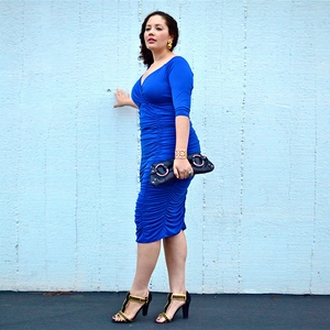 Detail of ruched V-neck bodycon dress showing navy blue fabric texture and side pleats
